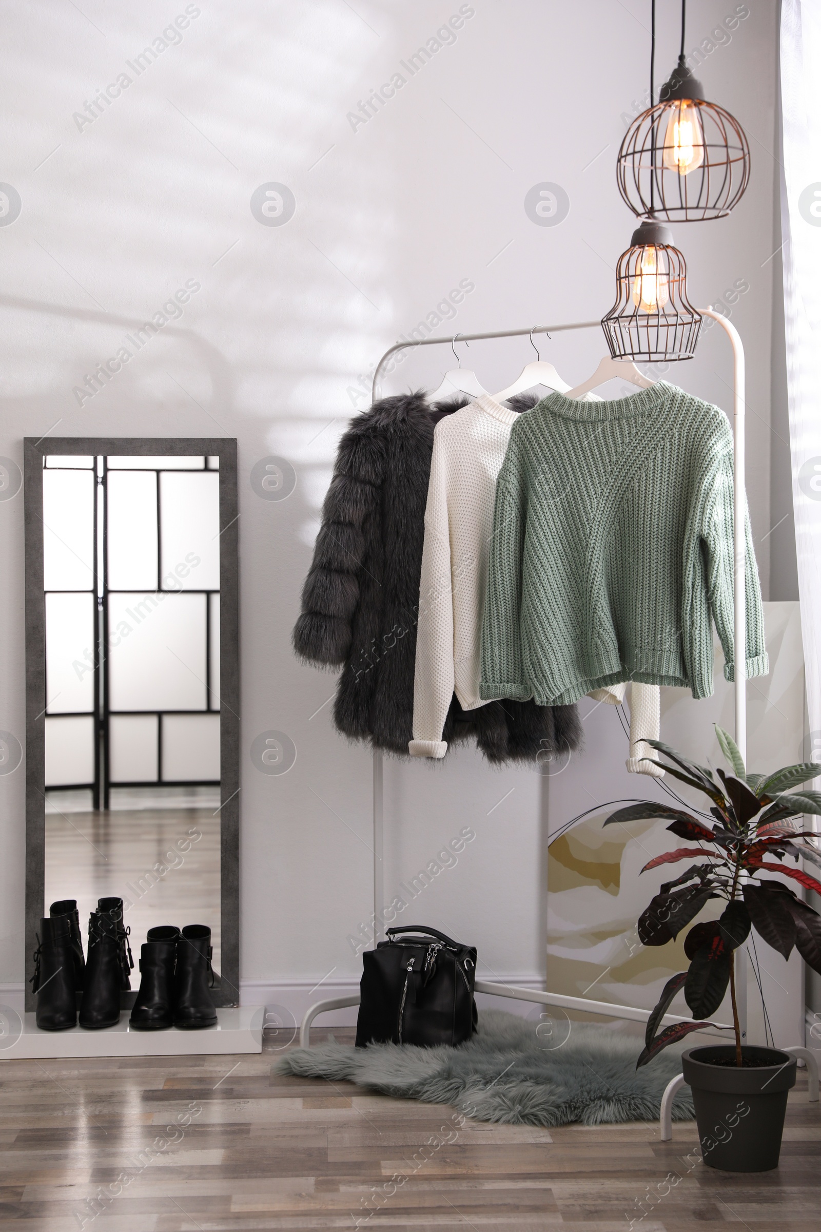 Photo of Stylish warm clothes on rack in dressing room interior