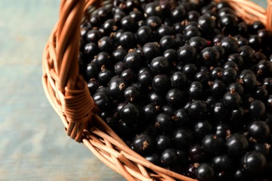 Photo of Ripe blackcurrants in wicker basket on wooden rustic table, closeup