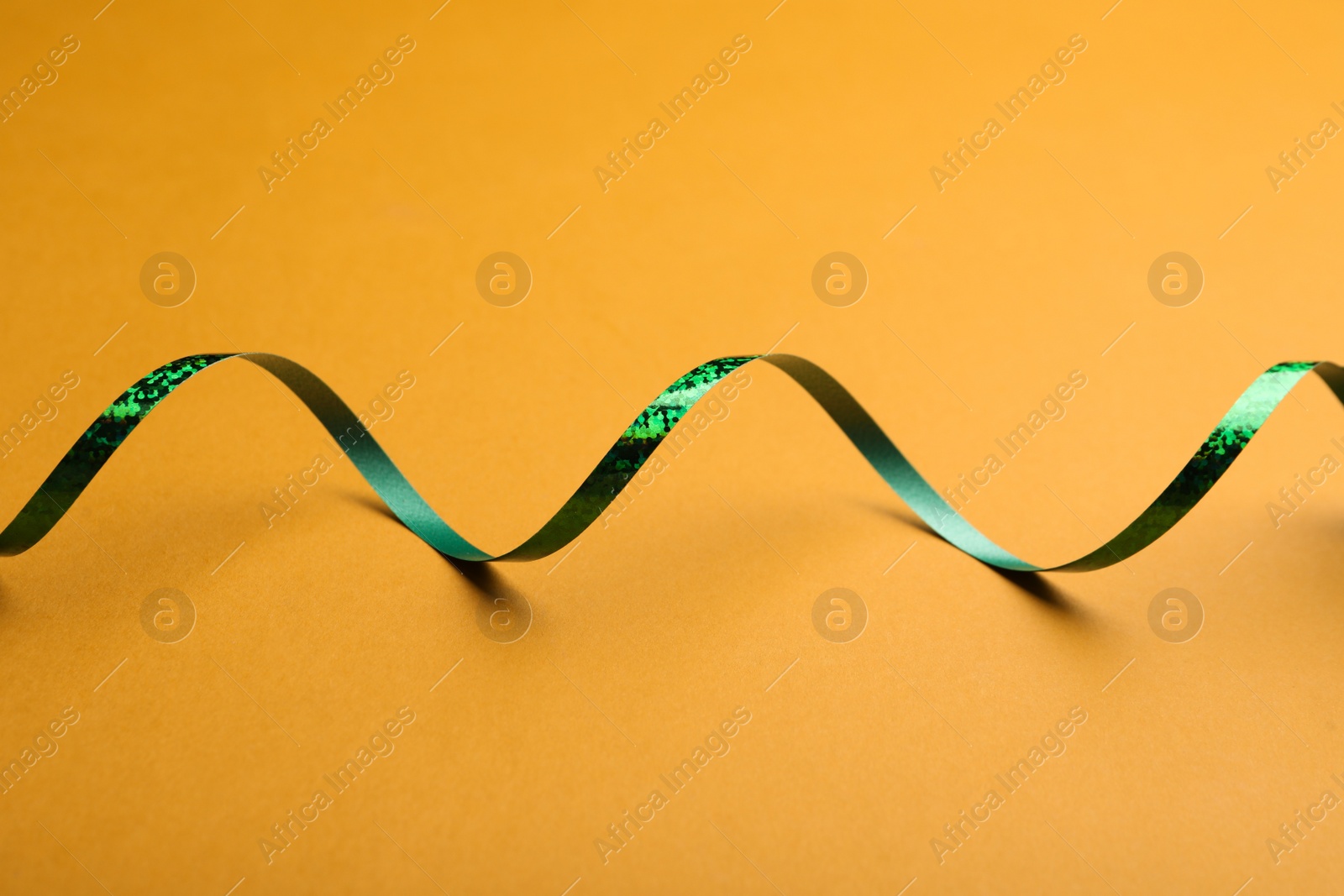 Photo of Shiny green serpentine streamer on orange background