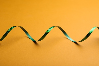 Shiny green serpentine streamer on orange background