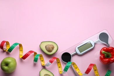 Electronic scales, measuring tape and food on pink background, flat lay. Space for text