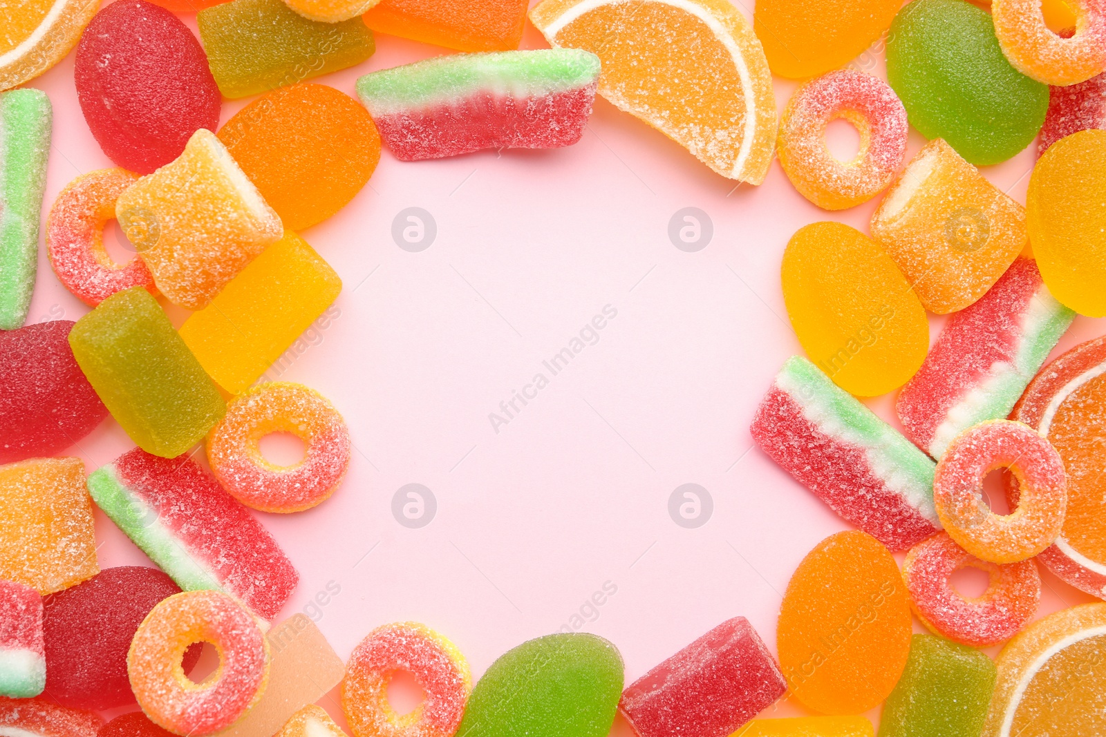 Photo of Frame made with tasty jelly candies on color background, top view. Space for text