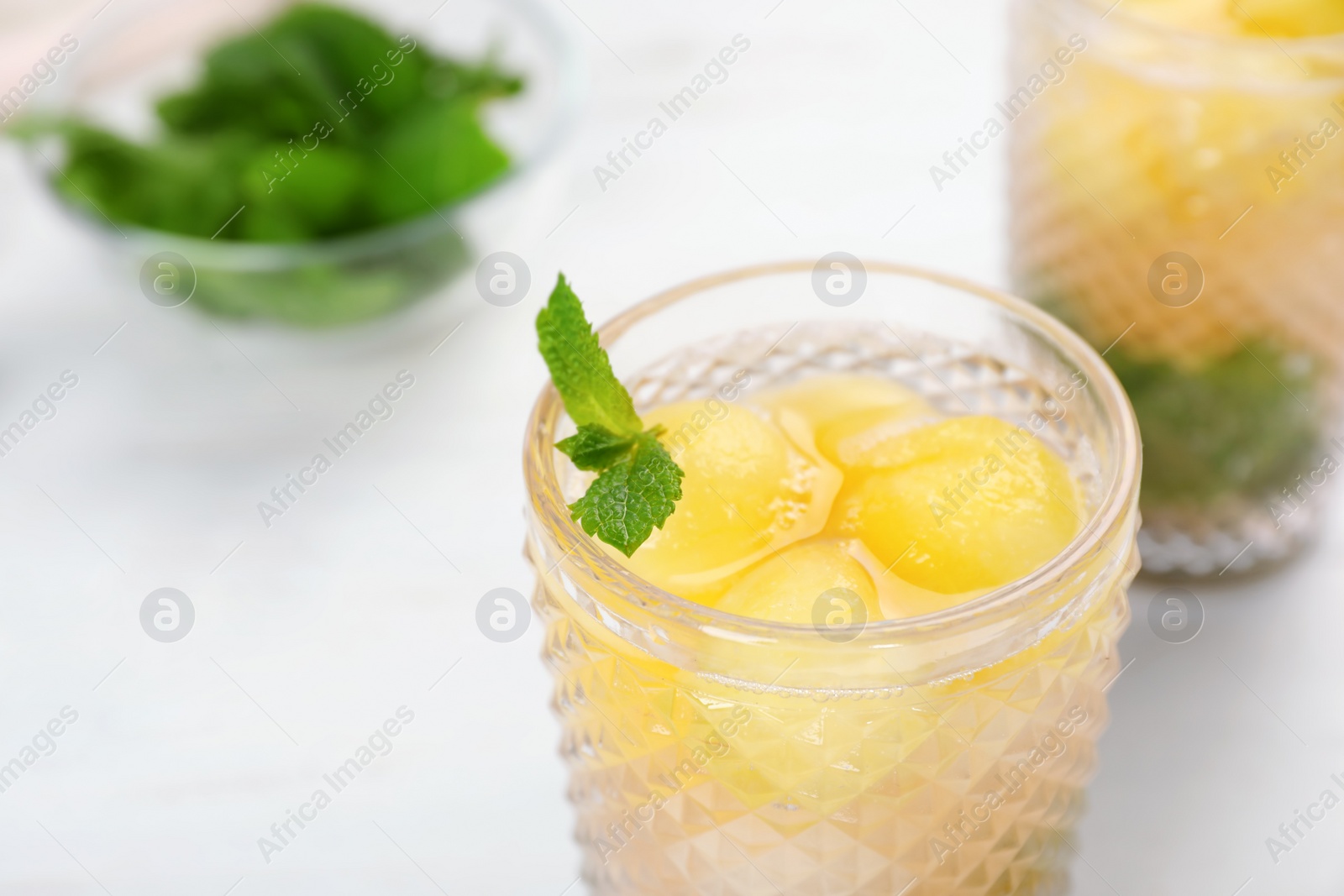 Photo of Glass with tasty melon ball drink on table, closeup