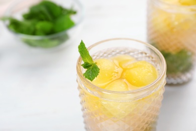 Photo of Glass with tasty melon ball drink on table, closeup