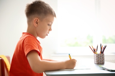 Cute little child doing assignment at desk in classroom. Elementary school