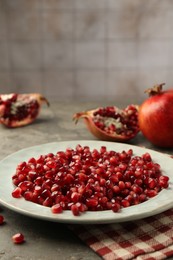 Photo of Tasty ripe pomegranate grains on grey table