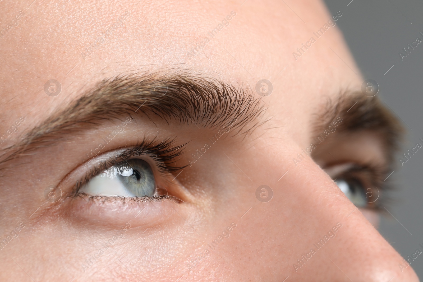 Photo of Closeup view of young man with beautiful eyes on grey background