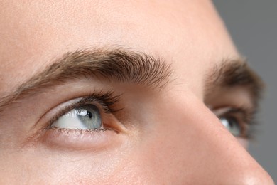 Photo of Closeup view of young man with beautiful eyes on grey background