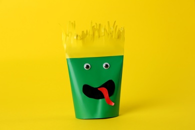 Photo of Funny green monster on yellow background. Halloween decoration