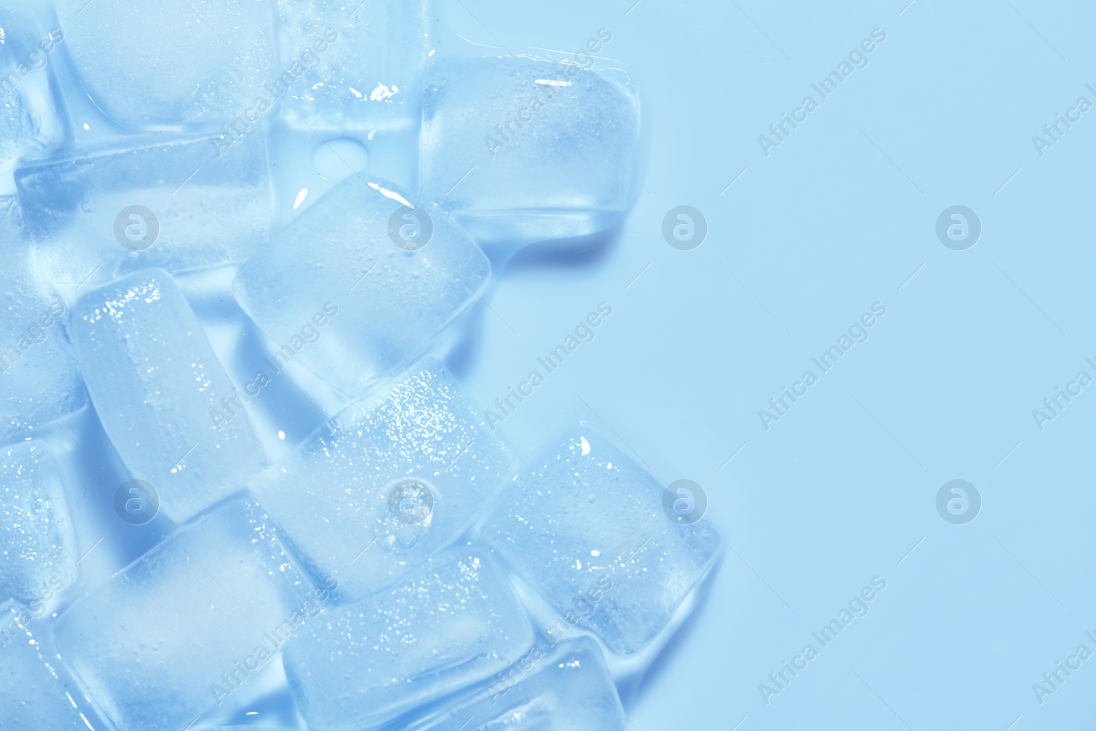 Photo of Melting ice cubes on color background, top view. Space for text