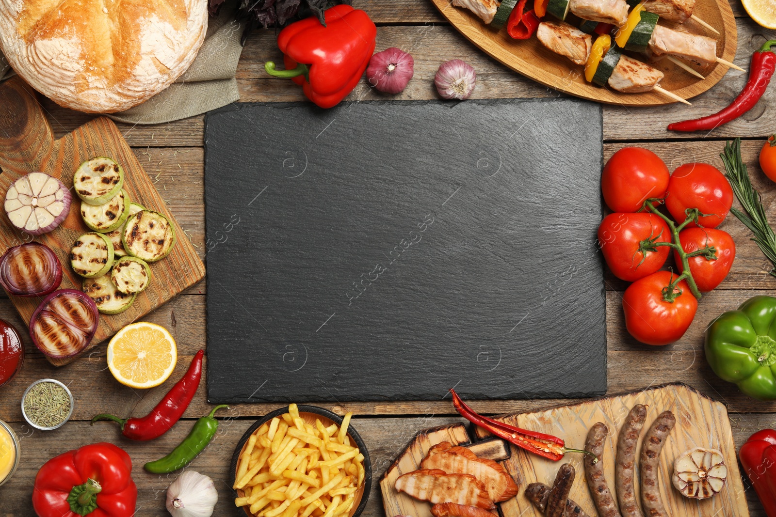 Photo of Flat lay composition with barbecued meat and vegetables on wooden table. Space for text