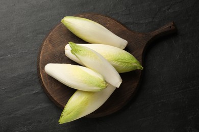 Photo of Fresh raw Belgian endives (chicory) on black table, top view
