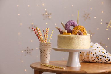 Photo of Delicious cake decorated with sweets and festive items on wooden table