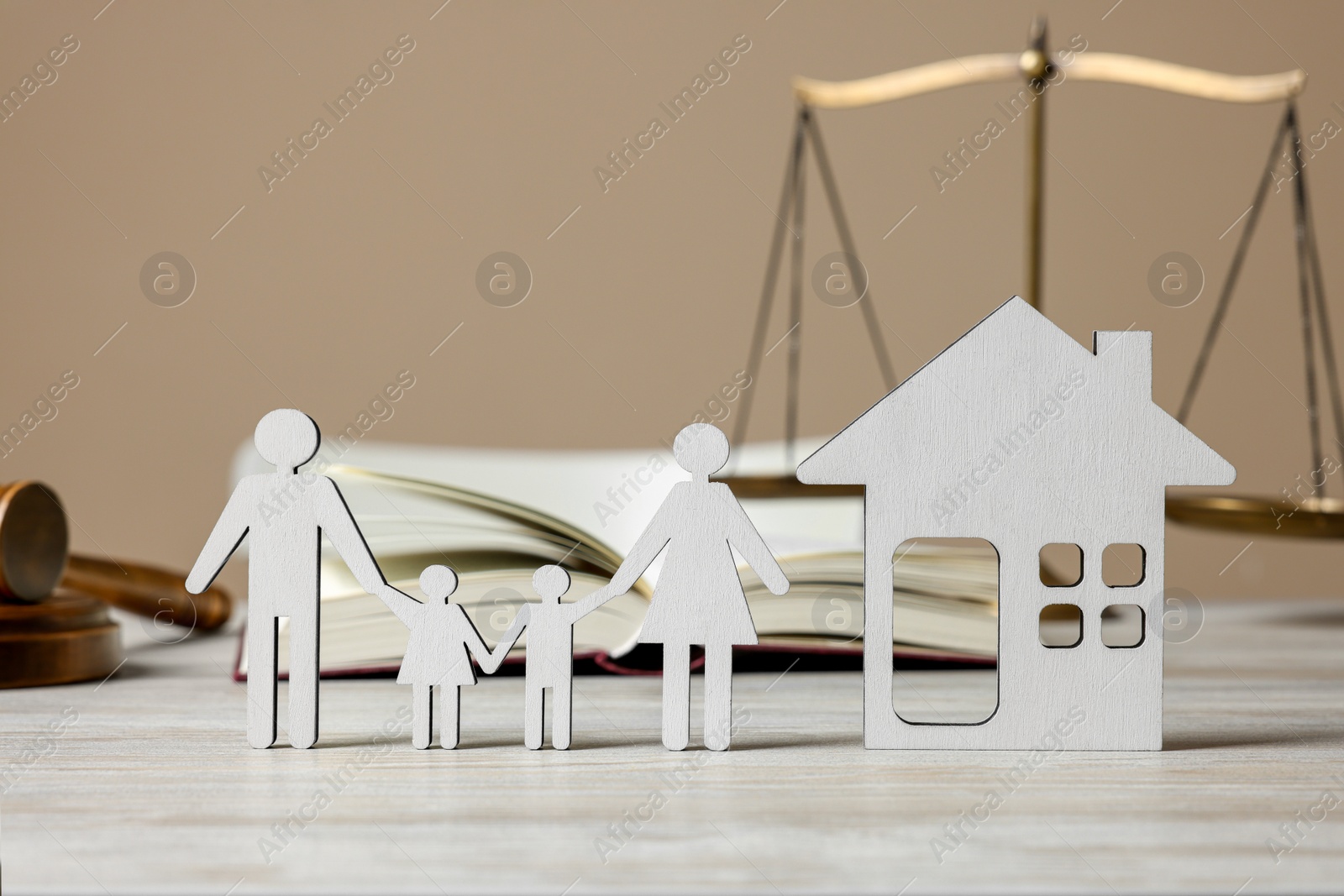 Photo of Family law. Figures of parents with children, house, book, scales of justice and gavel on wooden table