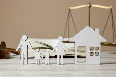 Photo of Family law. Figures of parents with children, house, book, scales of justice and gavel on wooden table
