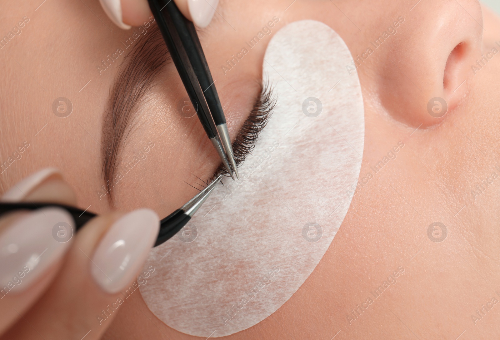 Photo of Young woman undergoing eyelash extension procedure, closeup