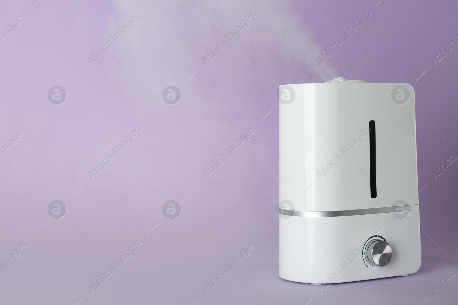 Photo of Modern air humidifier on violet background. Space for text