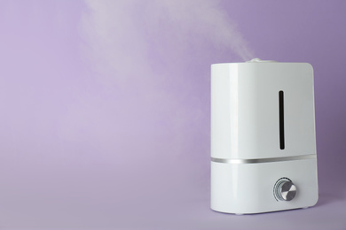 Photo of Modern air humidifier on violet background. Space for text