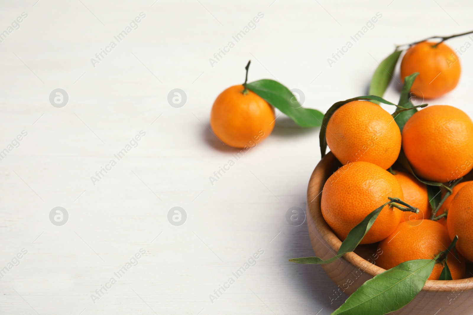 Photo of Fresh ripe tangerines in bowl on table. Space for text