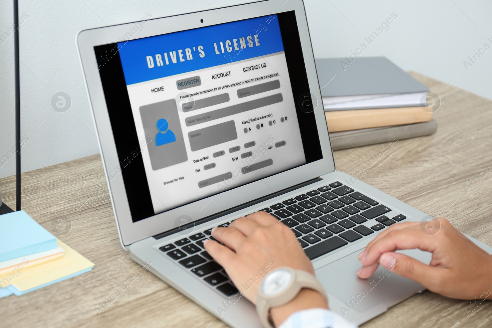 Photo of Woman using laptop to fill driver's license application form at table in office, closeup