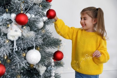 Cute little girl decorating Christmas tree at home