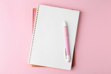 Photo of Notebooks and pen on pink background, top view