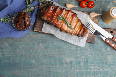 Photo of Tasty grilled ribs served on light blue wooden table, flat lay. Space for text