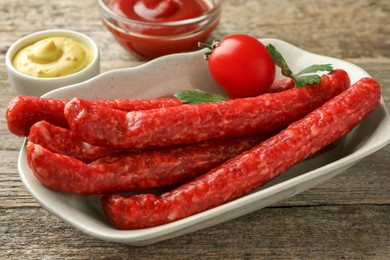 Thin dry smoked sausages served on old wooden table, closeup