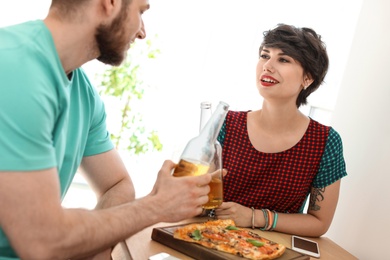 Photo of Young couple eating delicious pizza indoors