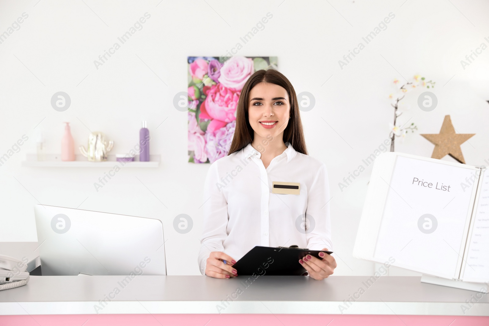 Photo of Young receptionist with clipboard at desk in beauty salon