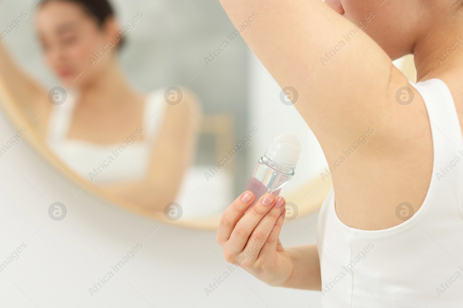 Photo of Beautiful woman applying deodorant near mirror in bathroom, selective focus