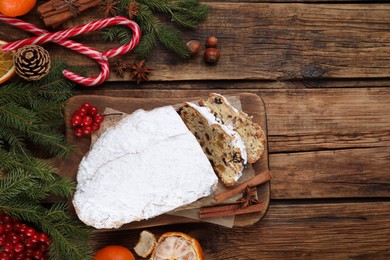 Traditional Christmas Stollen with icing sugar on wooden table, flat lay. Space for text