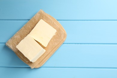 Block of tasty butter on light blue wooden table, top view. Space for text