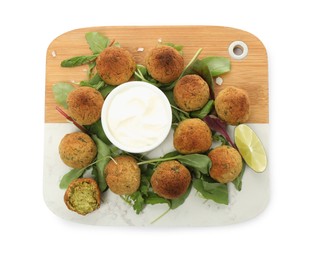 Photo of Delicious falafel balls with herbs, lime and sauce on white background, top view