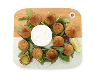 Delicious falafel balls with herbs, lime and sauce on white background, top view