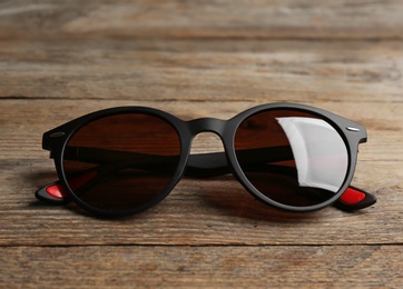 Stylish sunglasses on wooden background. Fashionable accessory