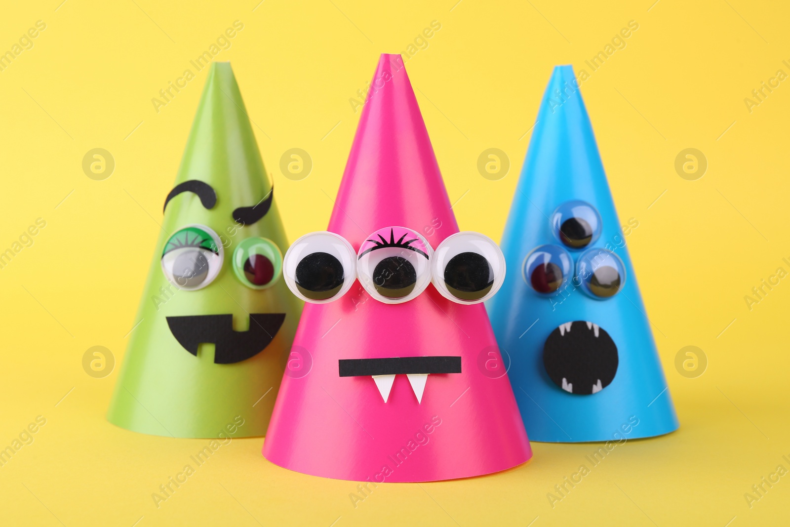 Photo of Spooky paper monsters on yellow background. Halloween decoration