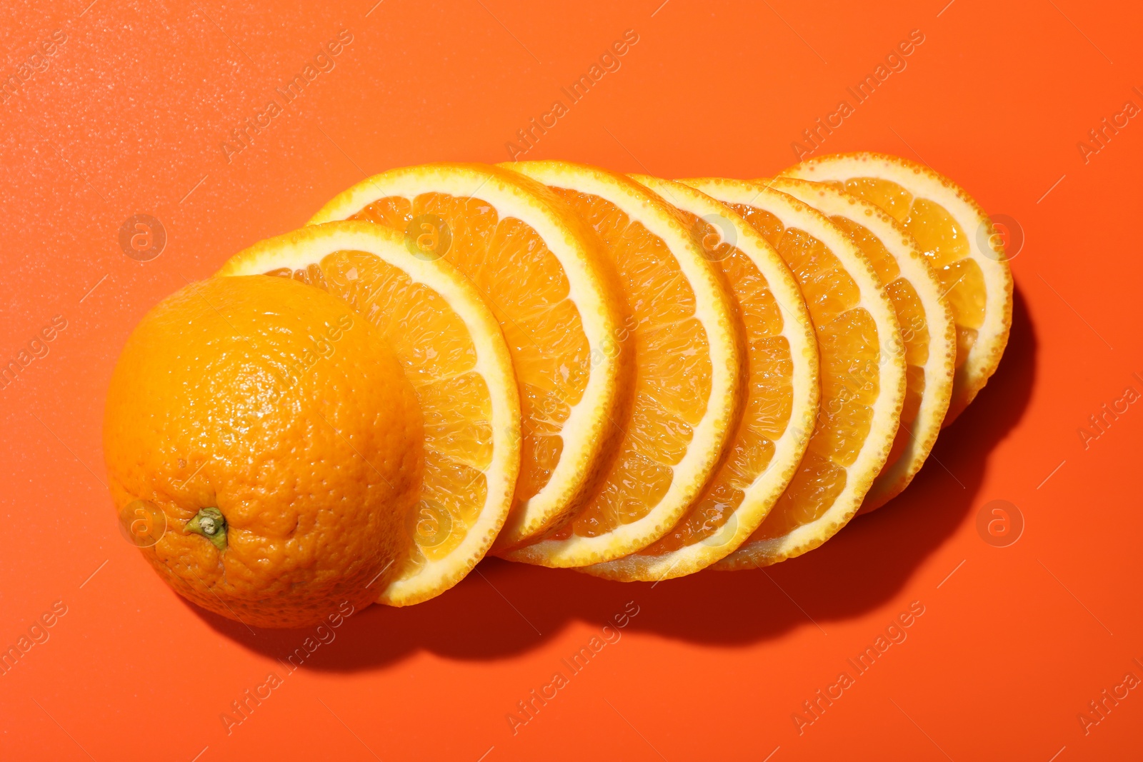 Photo of Slices of juicy orange on terracotta background, top view