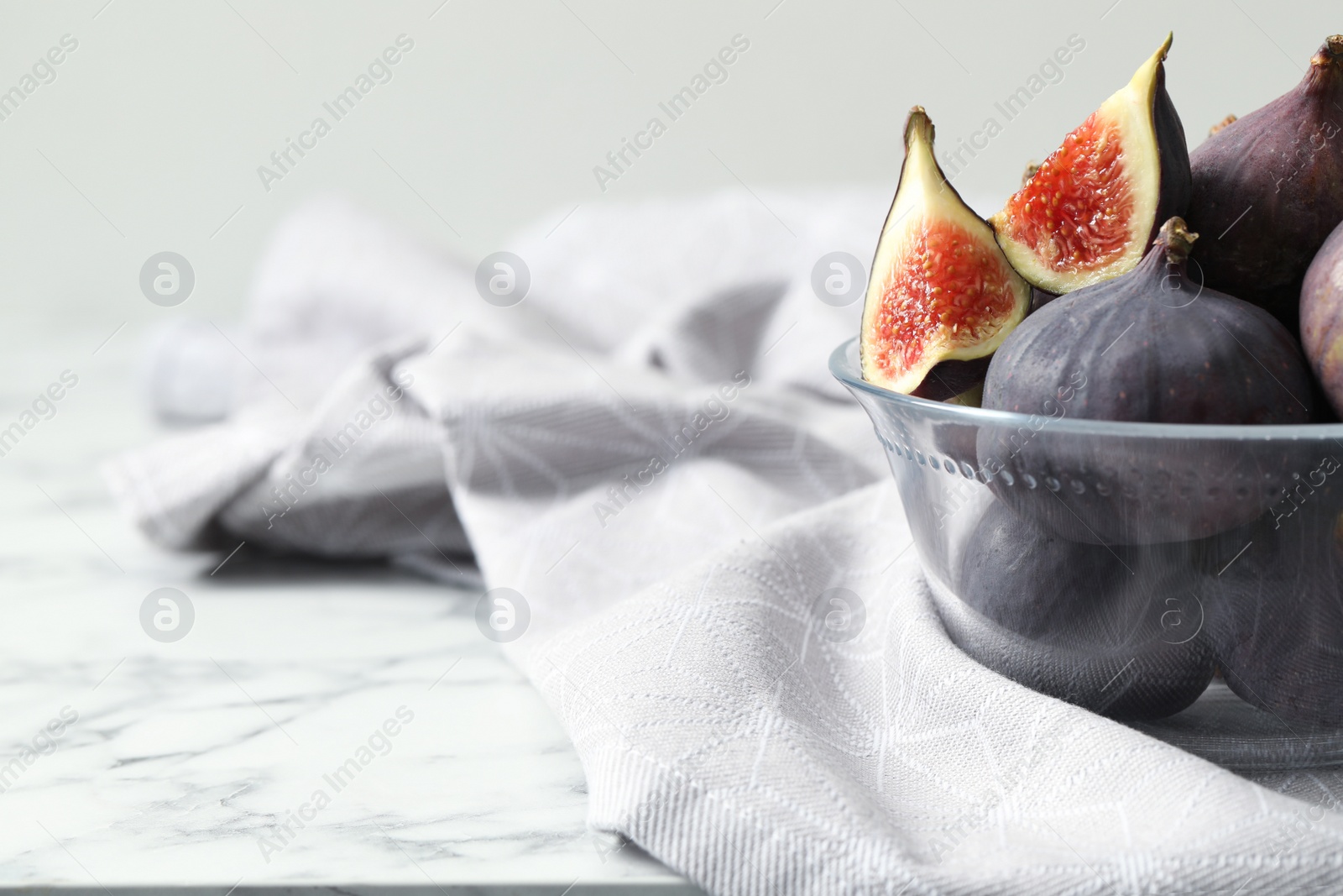 Photo of Whole and cut tasty fresh figs on white marble table, closeup. Space for text