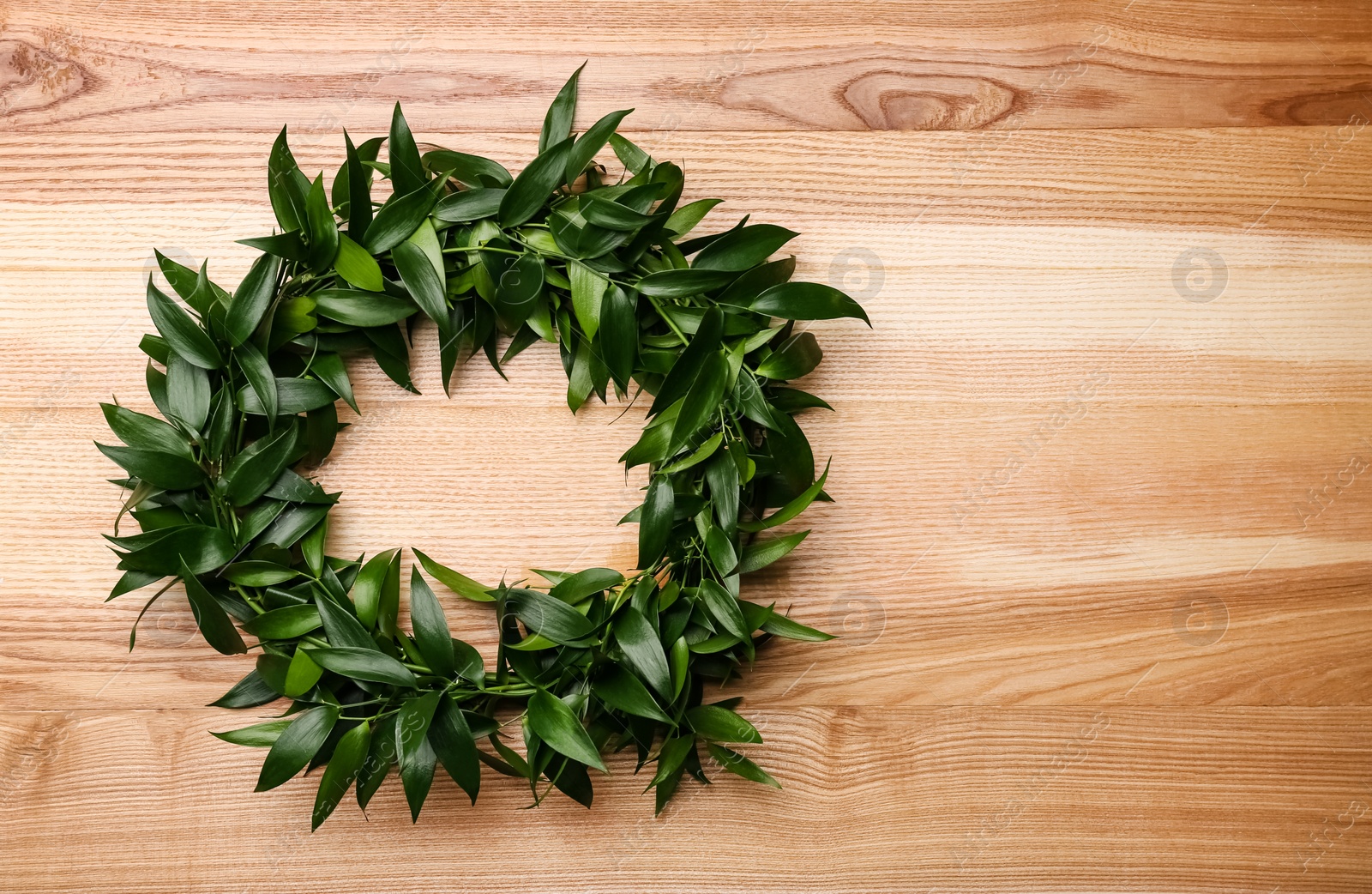 Photo of Beautiful handmade mistletoe wreath on wooden table, top view. Space for text