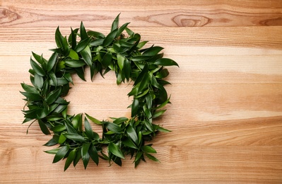 Photo of Beautiful handmade mistletoe wreath on wooden table, top view. Space for text