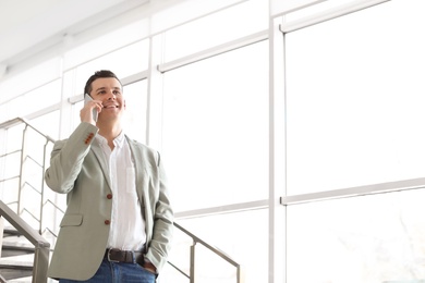 Photo of Portrait of confident businessman with mobile phone on stairs
