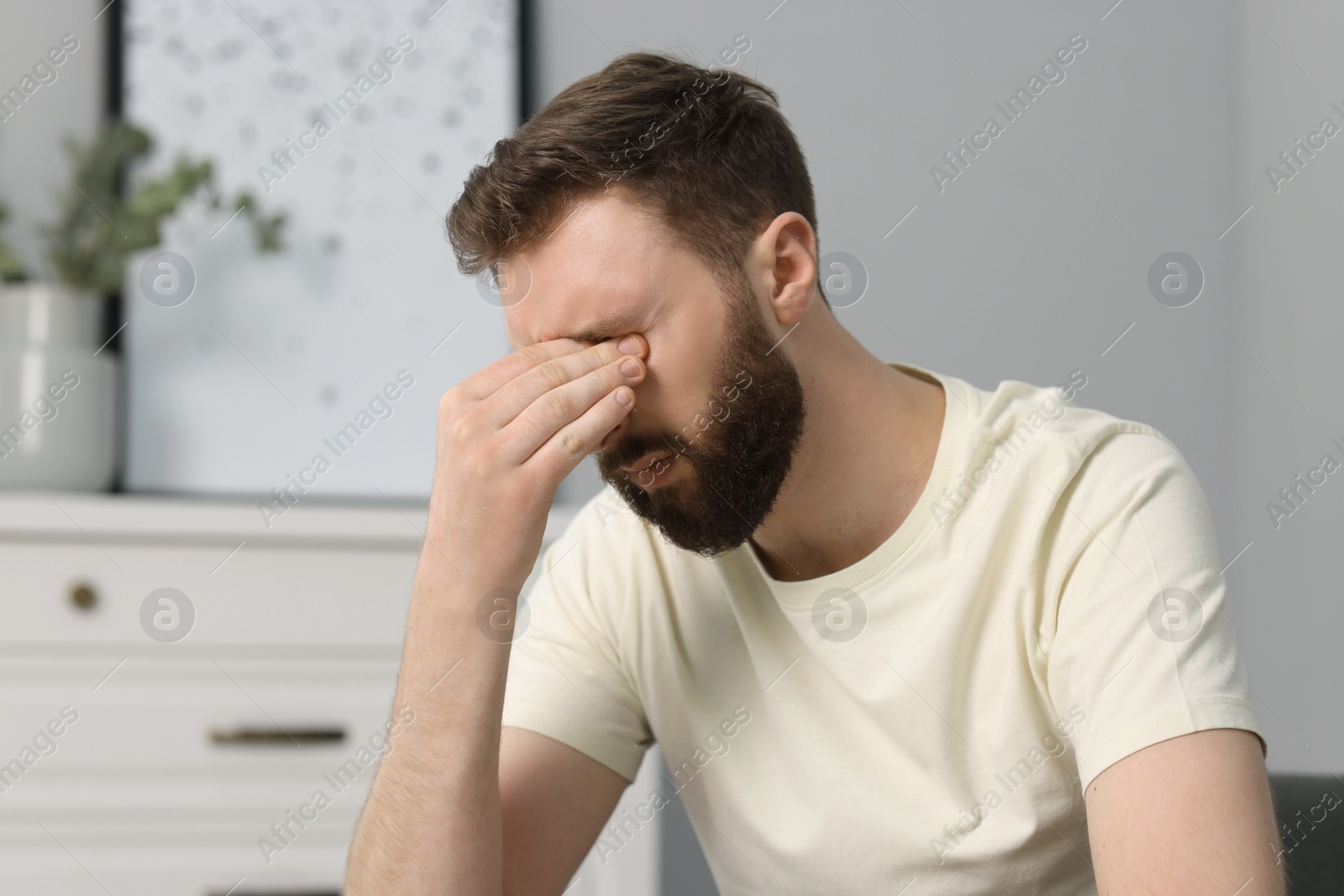 Photo of Overwhelmed man suffering from headache at home
