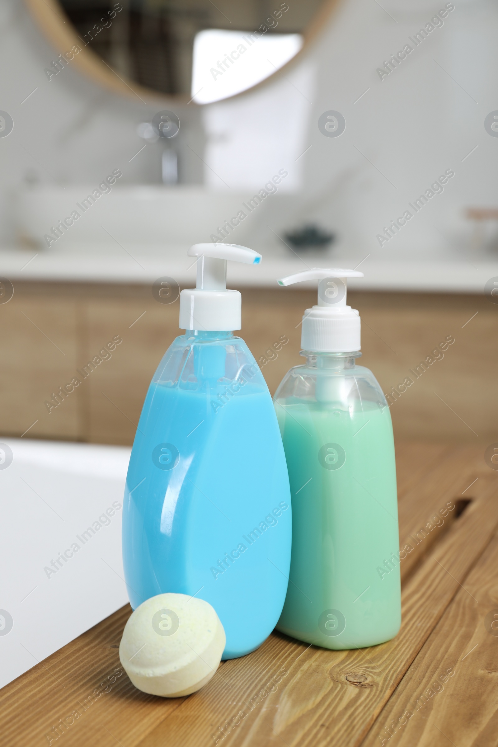 Photo of Bottles of shower gels and bath bomb on wooden table indoors