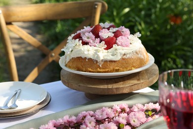 Photo of Beautiful spring flowers and delicious cake on table in garden