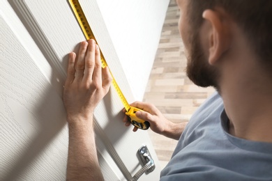 Photo of Man measuring door in room, closeup. Construction tool