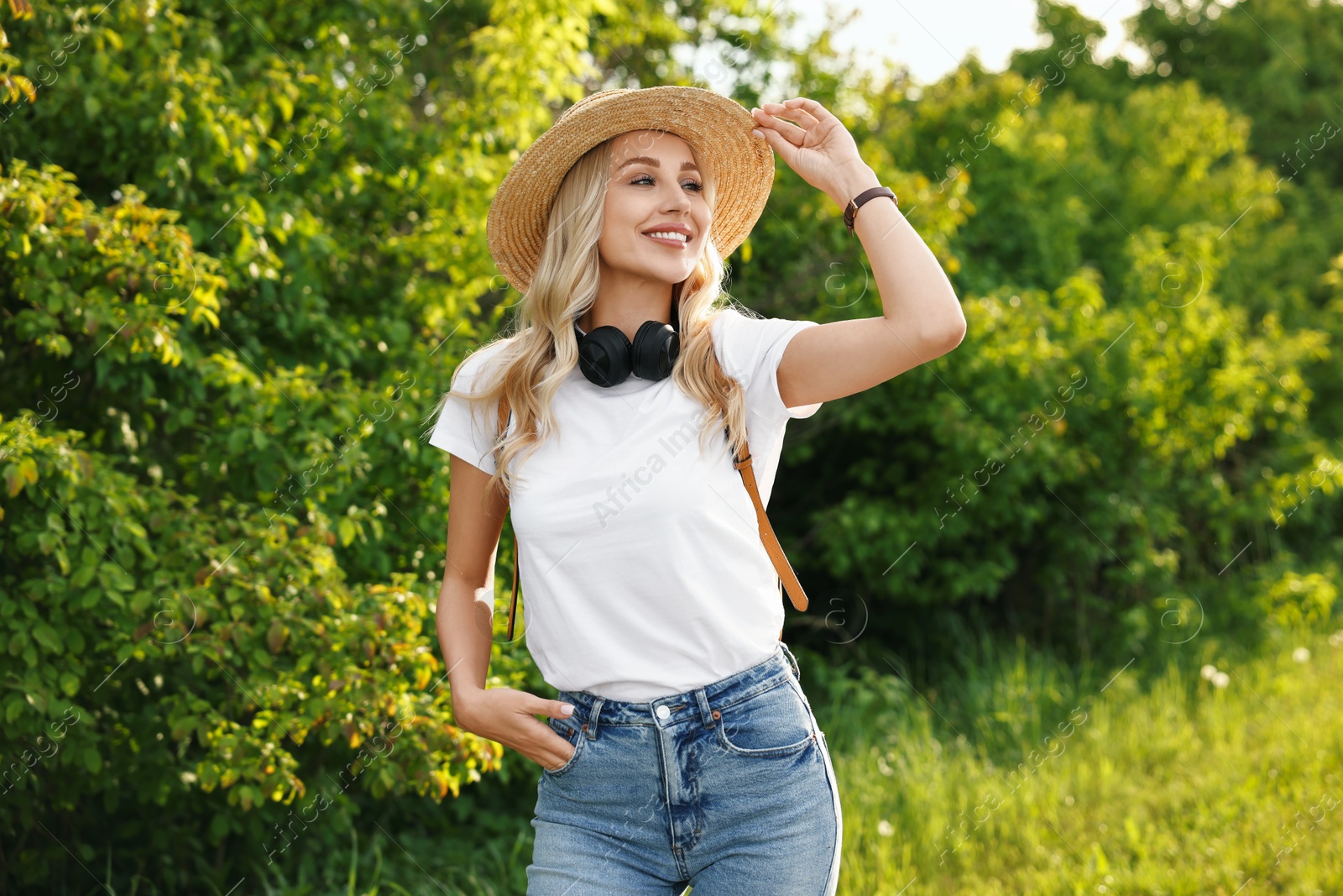 Photo of Happy young woman with headphones in park on spring day