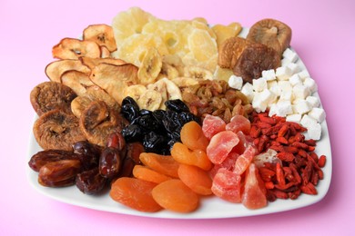 Photo of Plate with different dried fruits on violet background, closeup