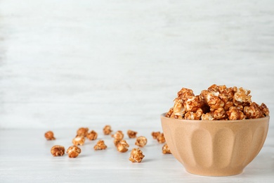 Bowl with tasty popcorn on white table. Space for text