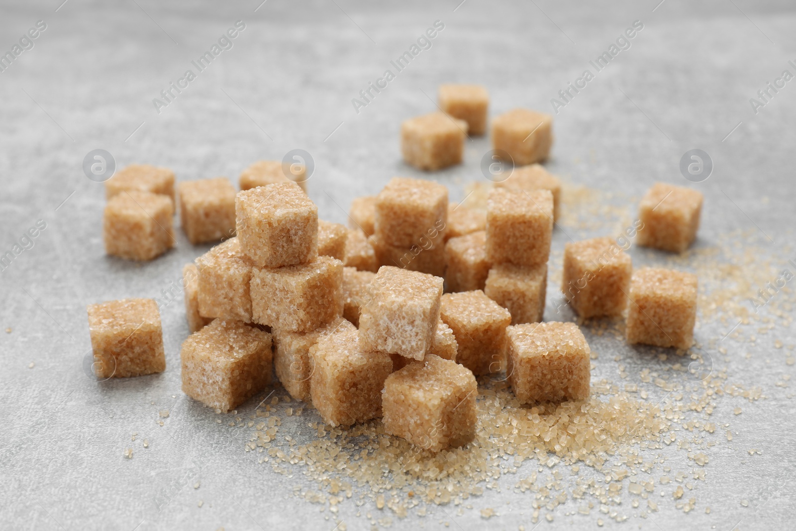 Photo of Many brown sugar cubes on grey table